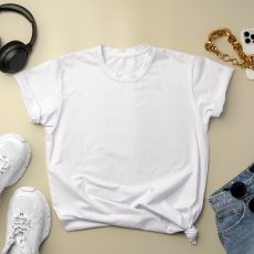White T-shirt, jeans and sneakers on beige background top view